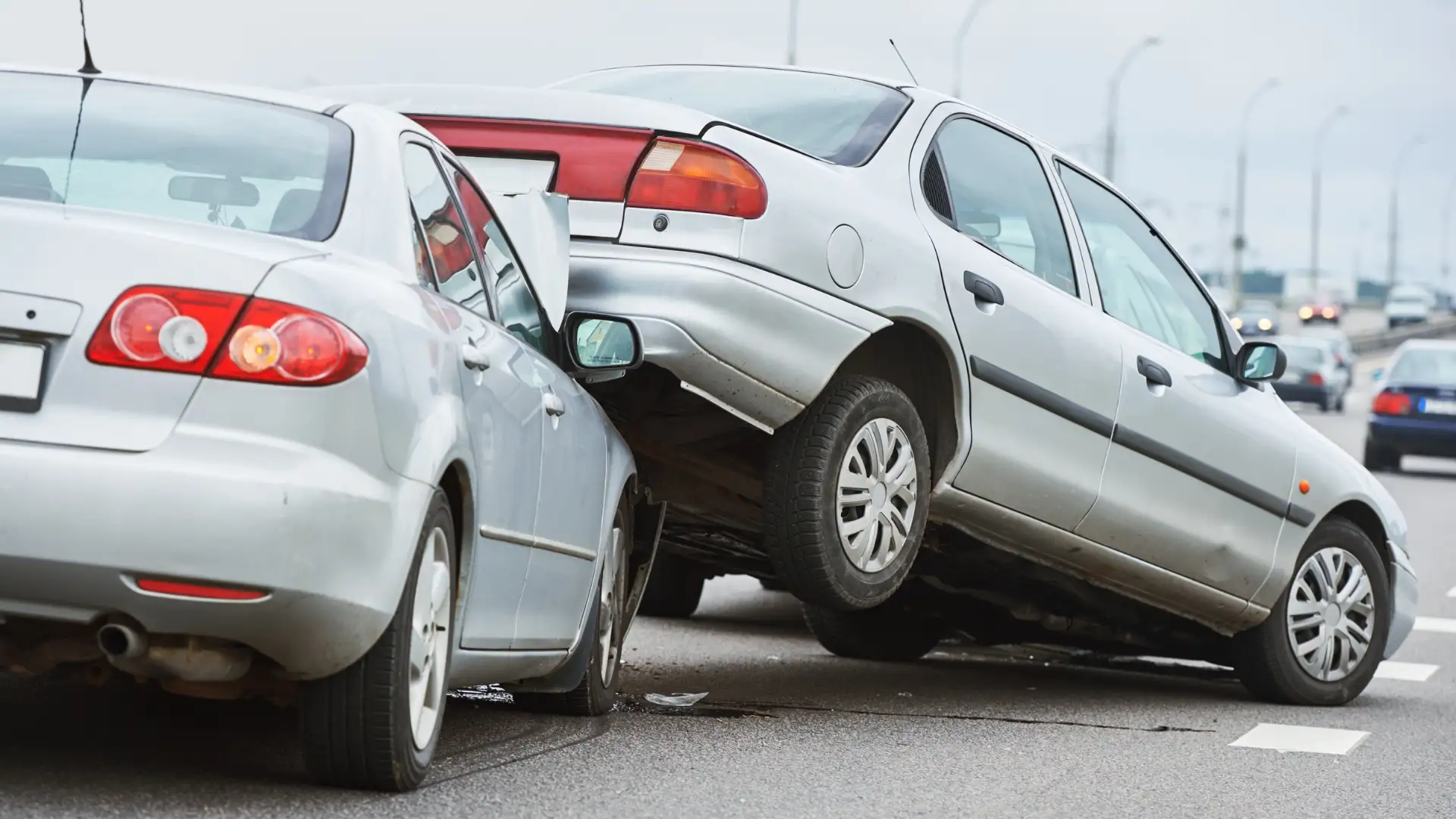 Multiple vehicle collision with one car partially mounted on another after a rear-end accident