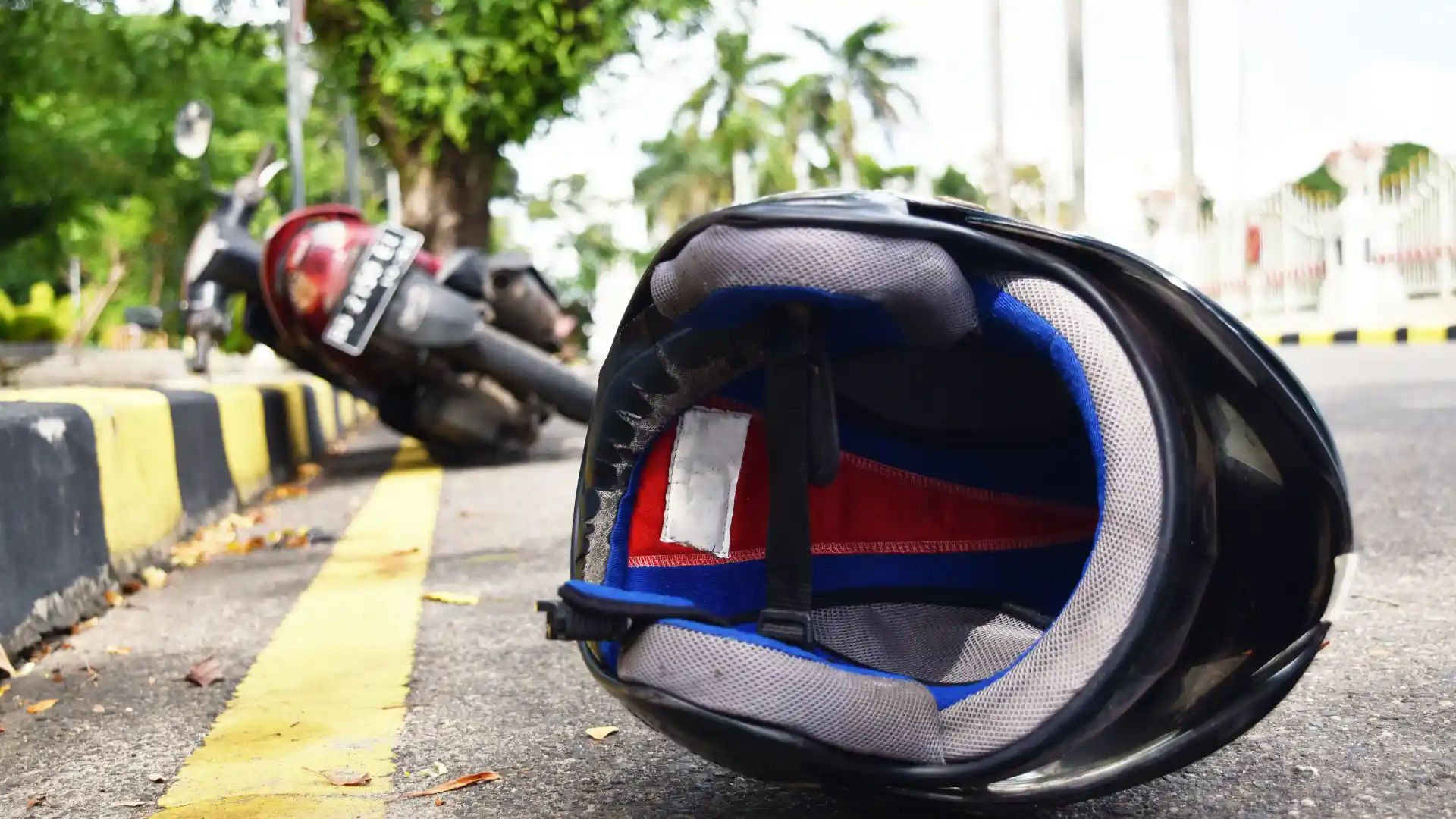 Close-up of a motorcycle helmet on the ground near an overturned motorcycle, indicating an accident scene.