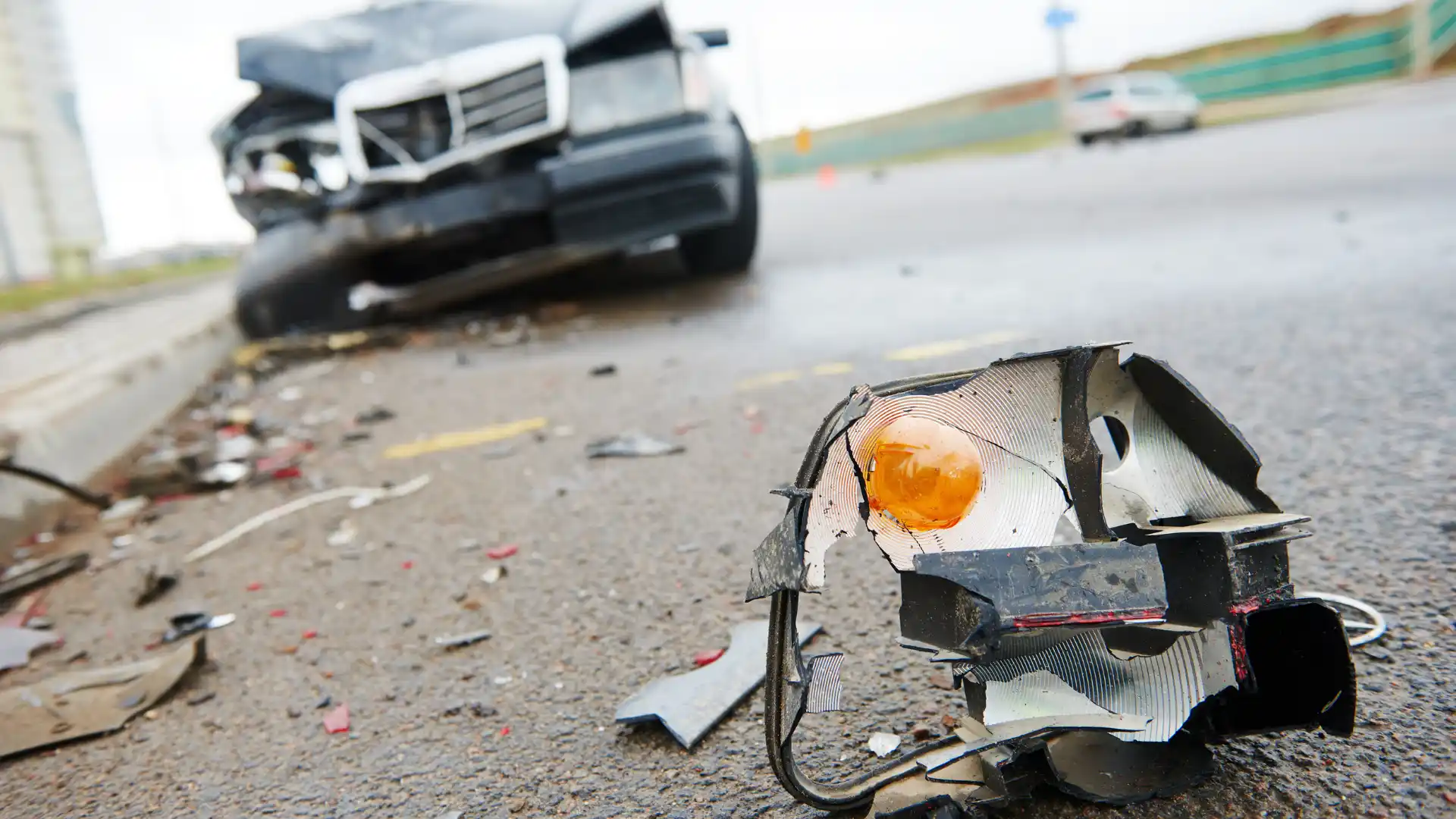 Damaged car parts and broken light lying on the road after an accident.