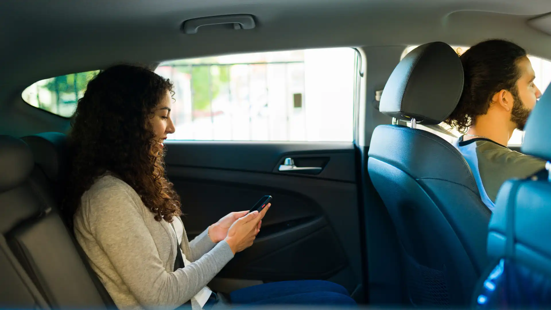 Woman sitting in the backseat of a car using her smartphone.