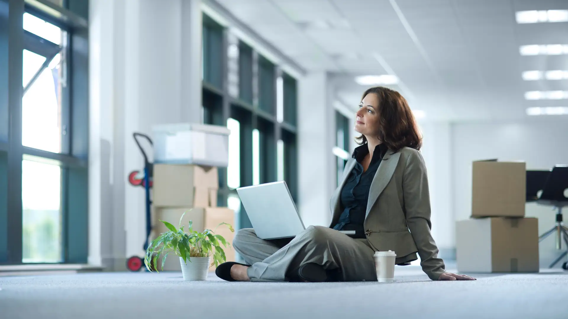 Businesswoman slipped on the floor with a laptop in an empty office space.