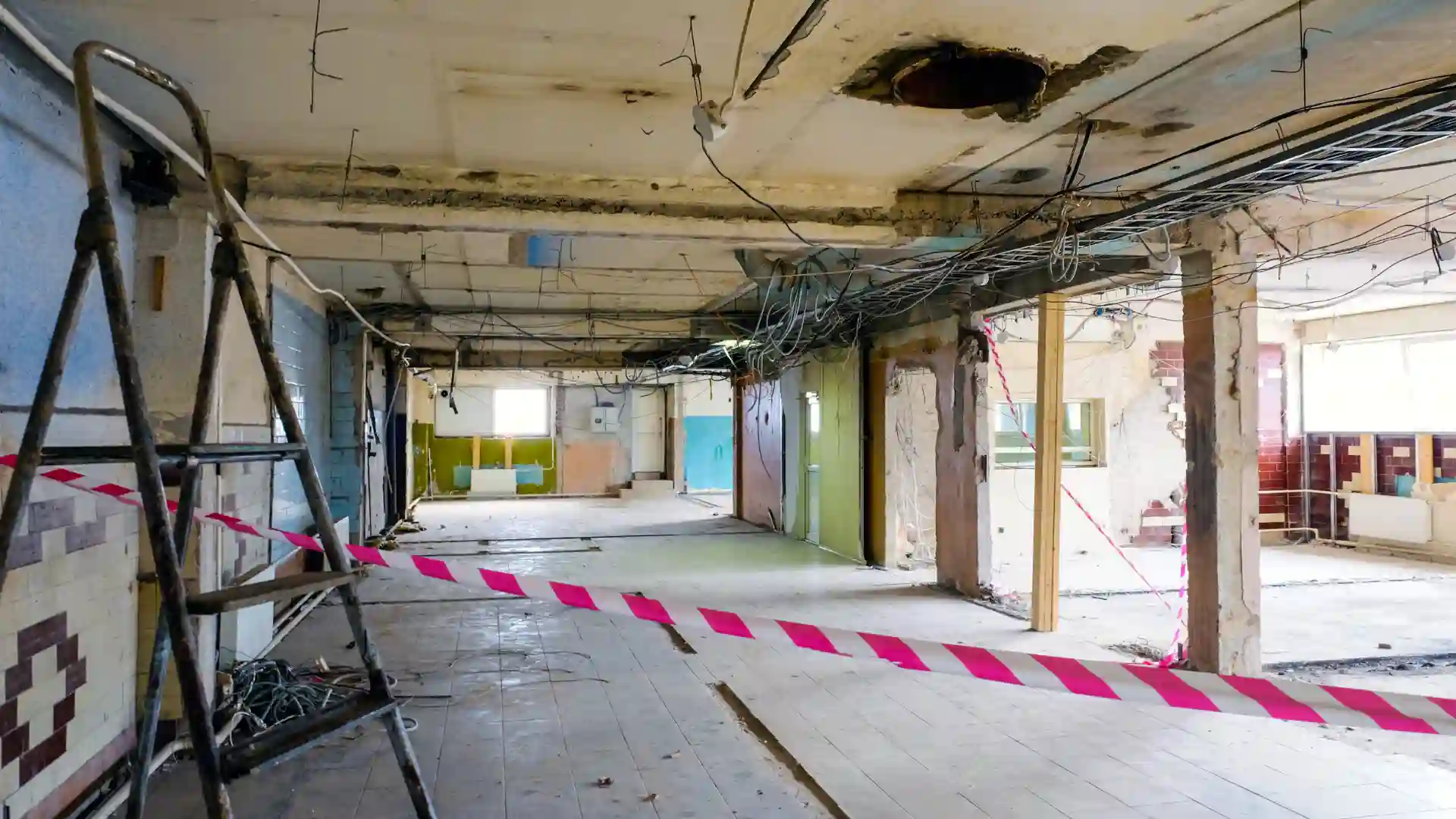 Interior of a damaged building marked with caution tape.