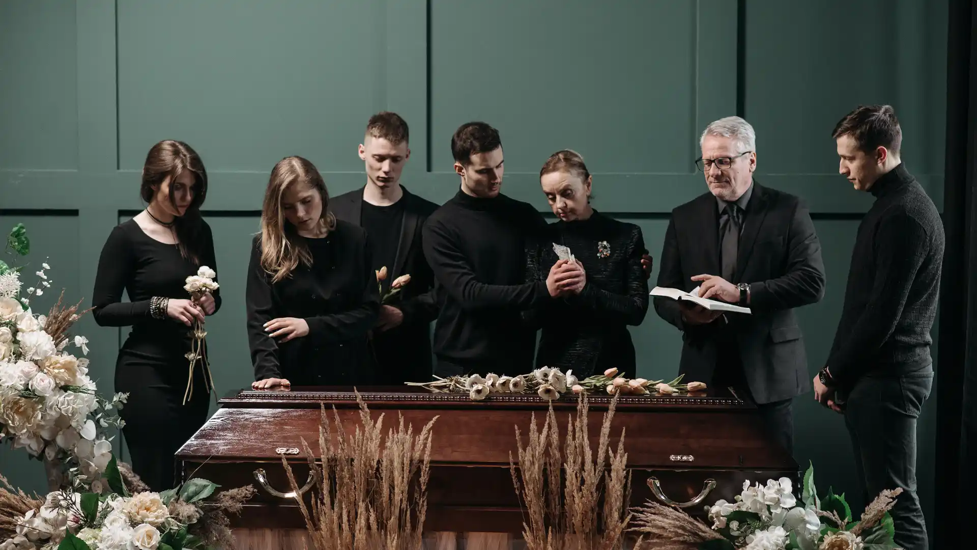 Mourners gathered around a casket during a funeral service, expressing grief and support.